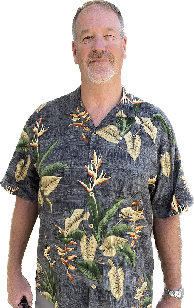 Man in Hawaiian shirt smiles at the camera.