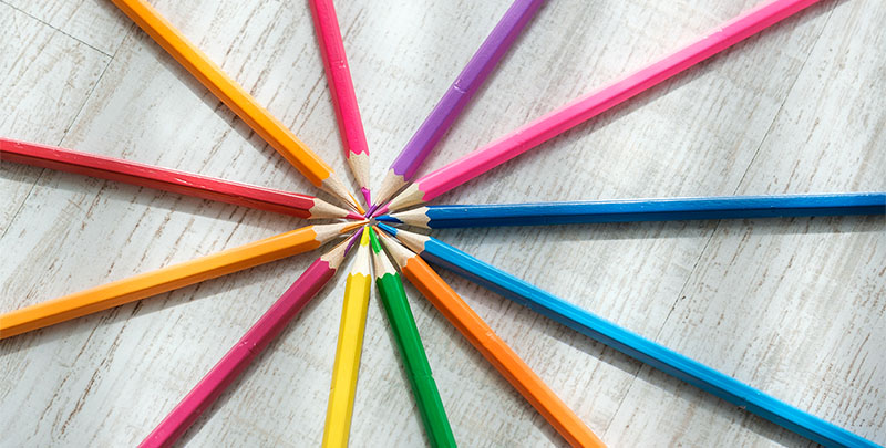 Colored pencils arranged in a circle on a wooden background
