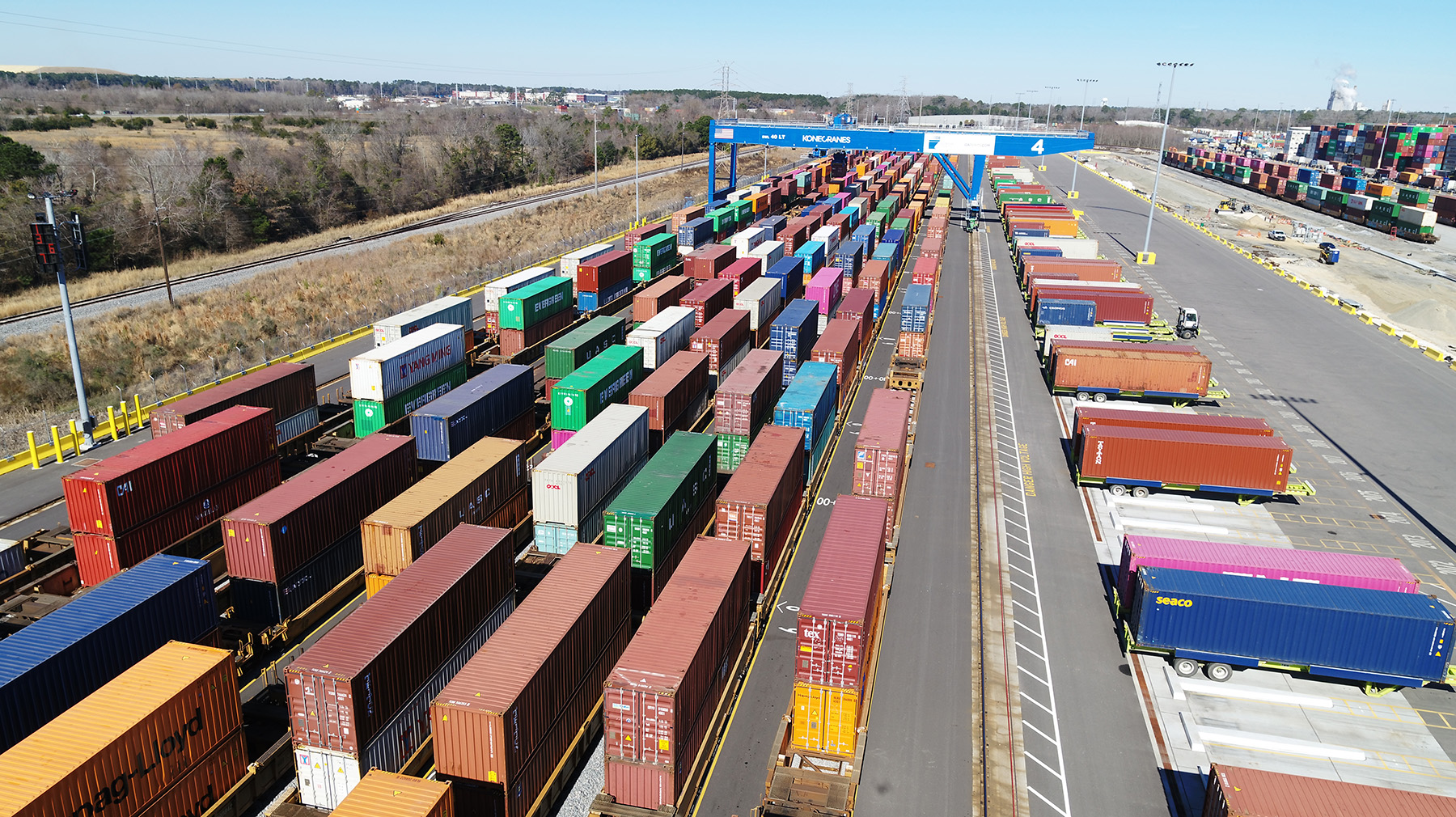 Multiple shipping containers in different colors sit in a shipping yard. 