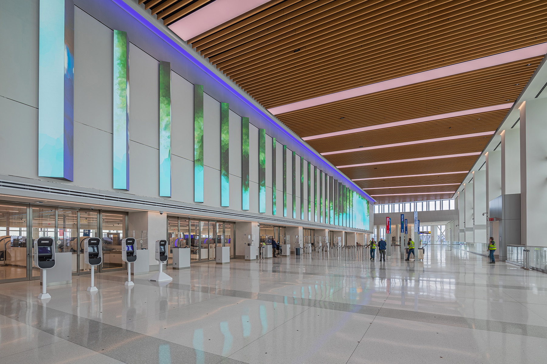 Photo shows the interior of a multistory airline terminal with its kiosks check-in stations. 