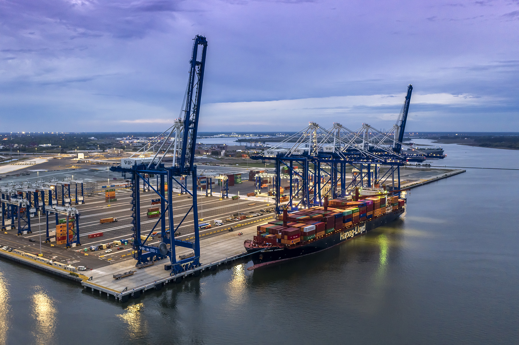 Image shows a water-based shipping terminal featuring a berth, container yard, and electric gantry cranes. 