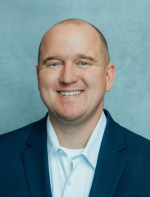 Portrait of Ben Ware - Man in blue jacket smiling at camera