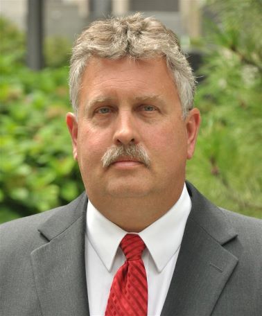 Portrait of Craig Hebebrand man in gray suit and red tie looking at camera
