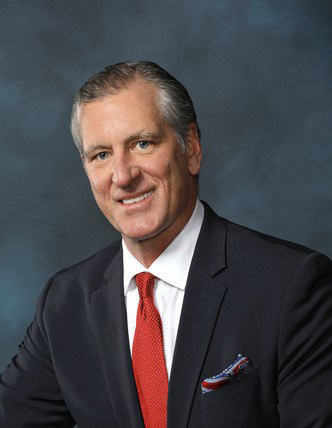 Portrait of Frederick Blickle, III. Man smiling at the camera wearing a suit and tie.