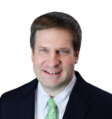 Portrait of Gregory Kuklinski - a man wearing a suit and a green tie with brown hair smiles at the camera