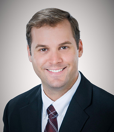 Portrait of Jacob Forrester. Man wearing a suit and tie smiling at the camera.