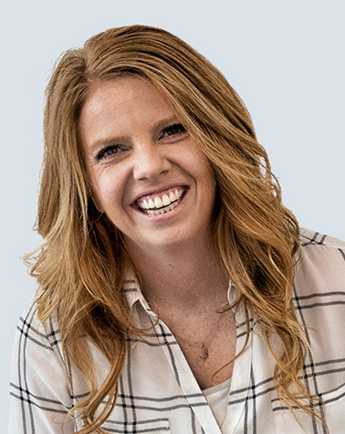 Portrait of Lauren Nuxoll. Woman with a long hair and striped shirt smiling at the camera.