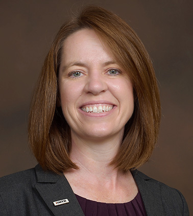 Portrait of LeAnne Napolillo. Woman with brown hair wearing a dark blazer smiling at the camera.