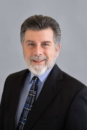 Portrait of Kenneth Rosenfield 2024 - Bearded man in dark suit smiling at camera