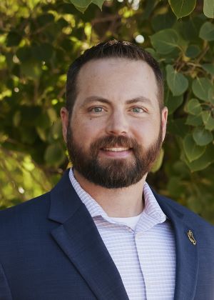 Portrait of Tim Brugger Bearded man in blue jacket smiling at camera