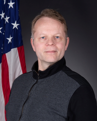 Portrait of Tor Anderzen man standing in front of US flag 