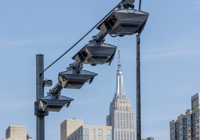 Streetscape view of traffic monitoring equipment with the downtown skyline visible in the background, part of the Central Business District Tolling Program.