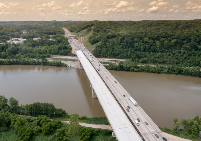 Aerial view of the I‑64 Kanawha River Bridge, carrying traffic across the river with forested hills in the background.