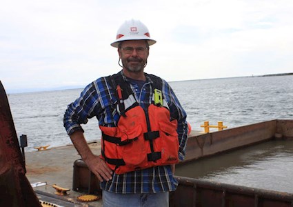 Photo of Tim Welp wearing a utility vest on a dock.