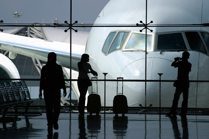 People standing at a terminal window overlooking the front of an airplane