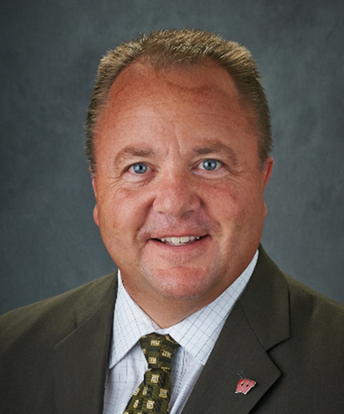 Portrait of David Noyce - a man wearing a suit smiling at the camera