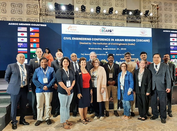 Pictured are 16 people in front of a stage in Goa, India at CECAR9.