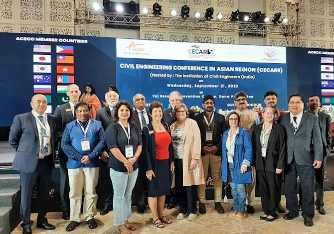 Pictured are 16 people in front of a stage in Goa, India at CECAR9.