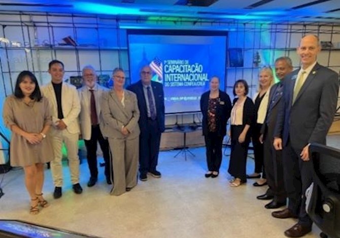 Ten people are in front of a screen facing the camera and smiling