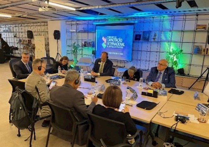 Eight people are sitting around a table with headphones on listening to a presentation.