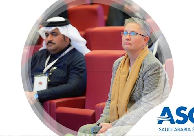 Two people sitting in an auditorium watching a presentation.