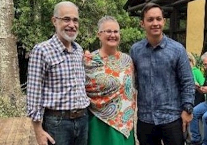 Three people are standing outside smiling at the camera.