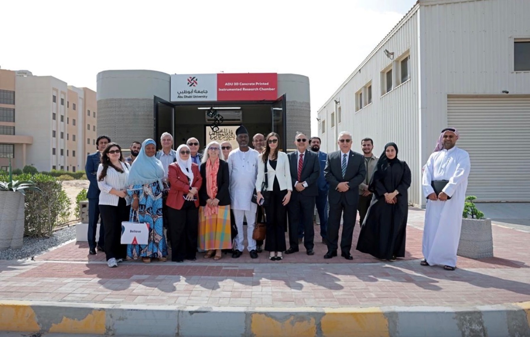 Event attendees in front of the 3D printed concrete building. 