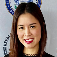 Woman with shoulder-length brown hair wearing a black lacy blouse smiles at the camera. 