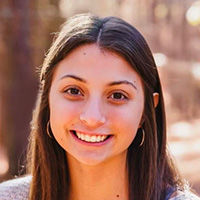 Young woman with brown hair smiles at the camera.