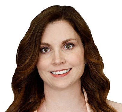 woman in pink blazer, white blouse, and black pants smiles.