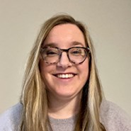 Woman in glasses and gray sweater.