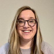 Woman in glasses and gray sweater.