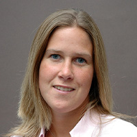 Woman blondish hair in a white button down looks at the camera.