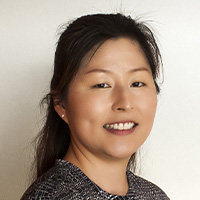 Woman in black and white patterned top smiles at the camera. 