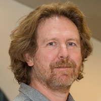Man with reddish hair in gray shirt looks at the camera.