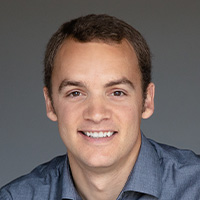 Man wears button-up shirt and smiles at the camera. 