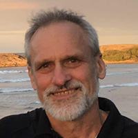 Man in black polo shirt smiles at the camera. 