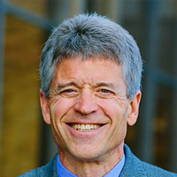 man in blue shirt and jacket smiles at the camera