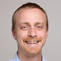 A man wearing white shirt smiles at the camera. 