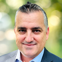 Man with graying slicked back hair smiles at the camera. 