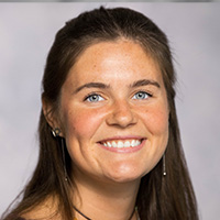 Woman with blue eyes and brown hair smiles at the camera. 