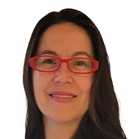 A woman with long dark hair and red-framed glasses looks out at the camera. 