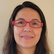Woman with brown hair and wearing glasses smiles at the camera.