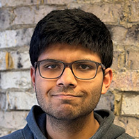 Man in dark grey sweater with glasses smiles at the camera