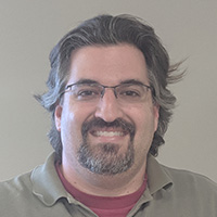 Man in gray shirt smiles at camera