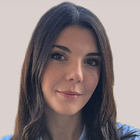 A woman with long dark hair in a blue shirt smiles at the camera. 