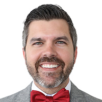 Man wears red bowtie and smiles at the camera. 