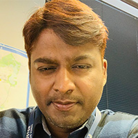 Man with tanned skin and reddish-brown hair looks at the camera. 