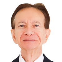 An adult man with hands crossed in front of him looks out at the camera. 