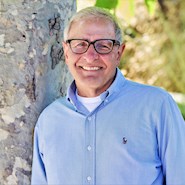 Man in blue shirt stands next to a tree